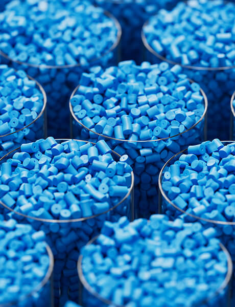 Blue plastic resin pellets packed in round metal containers, close-up view.